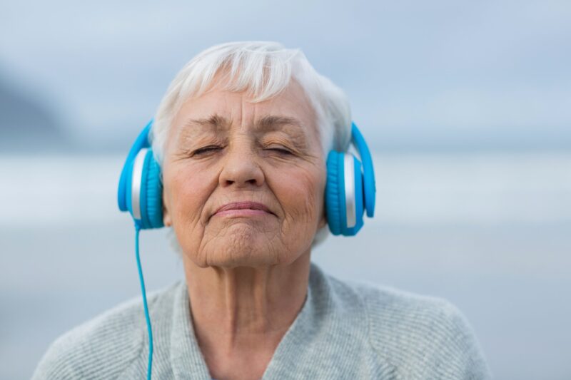 Senior woman with closed eyes, wearing headphones