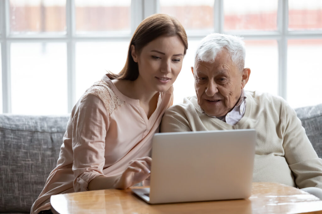 senior man on computer with caregiver