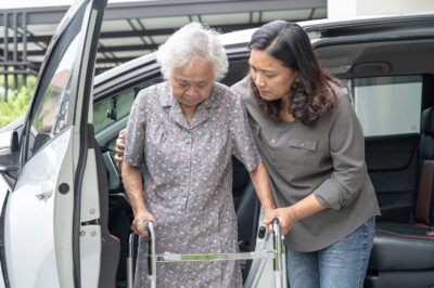 How do I help an older adult in and out of a car after hip surgery?