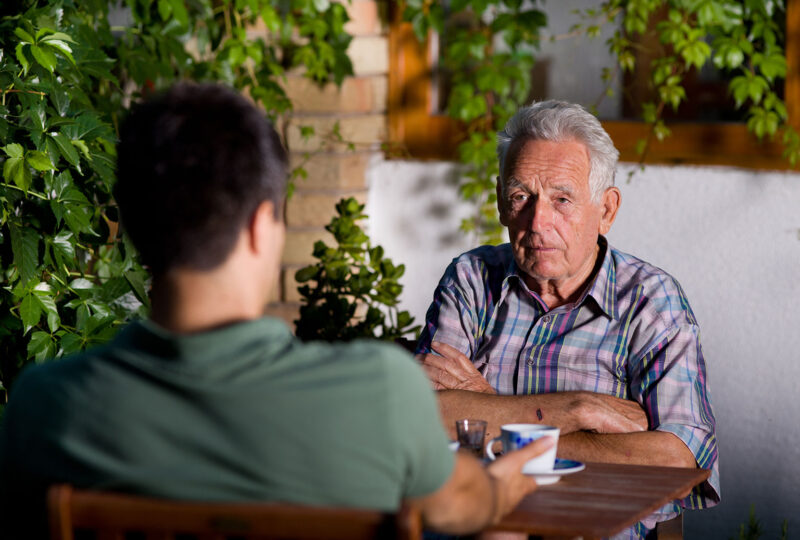 angry older man sitting with young man at table