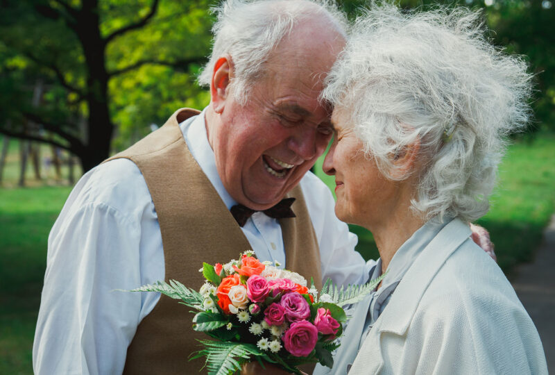 senior man and woman with flowers smiling