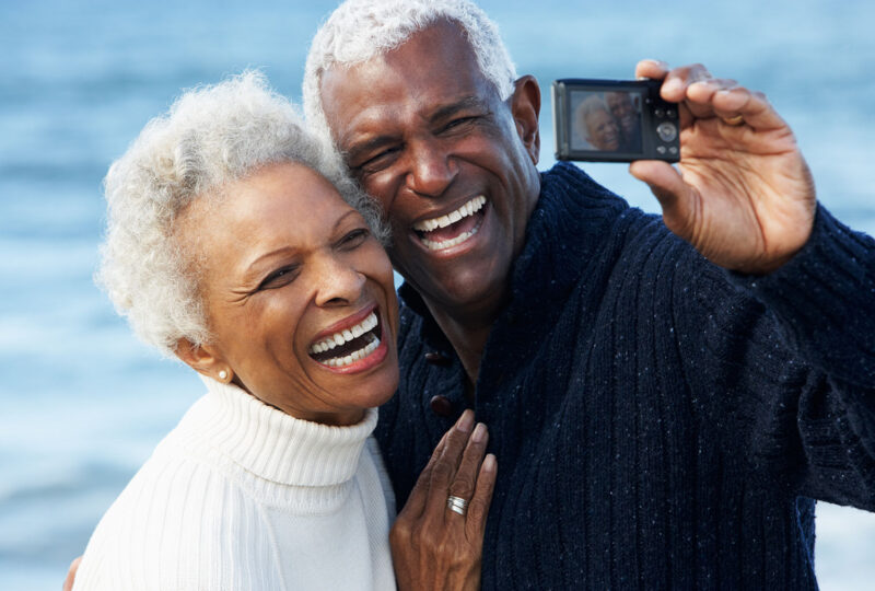 happy smiling older couple on beach posing for selfie