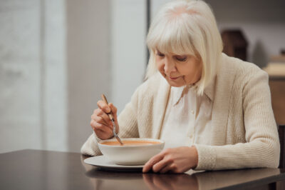 senior woman eating soup at table