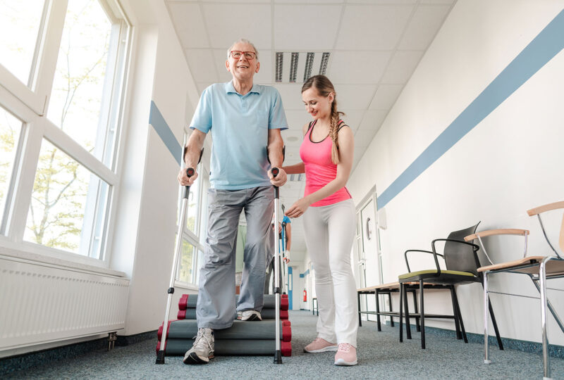 senior man on crutches with nurse rehabilitation