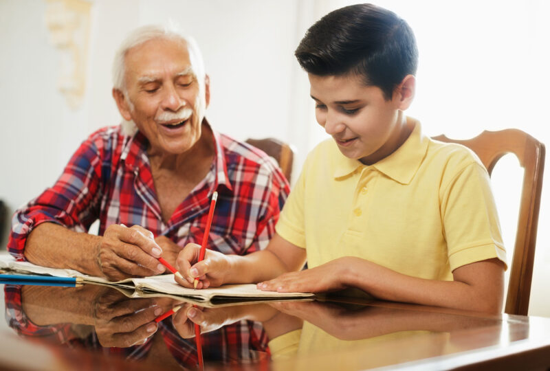 older man helping young child with homework