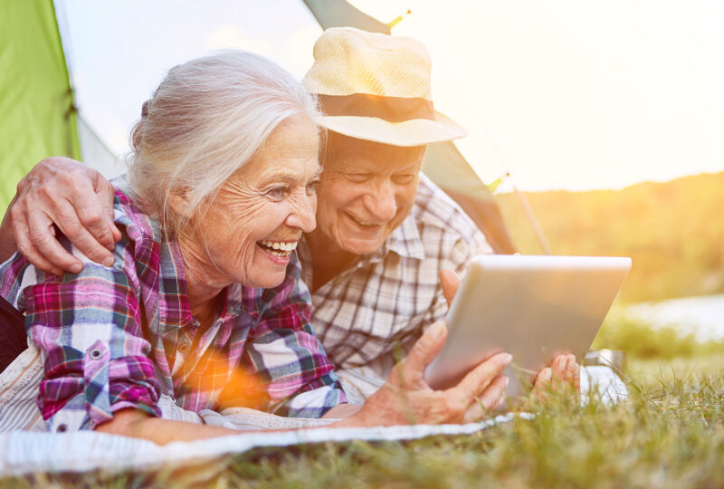 senior elderly man woman laughing at tablet