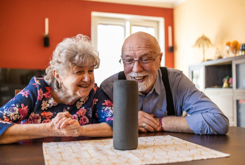 elderly senior man woman couple talking to smart speaker