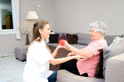 young woman working with senior woman holding weight physical therapy