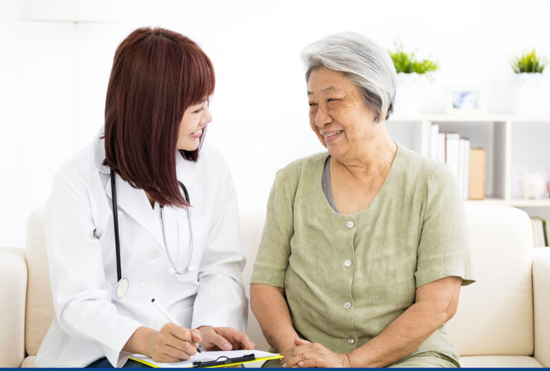 younger woman nurse smiling at older woman, also smiling