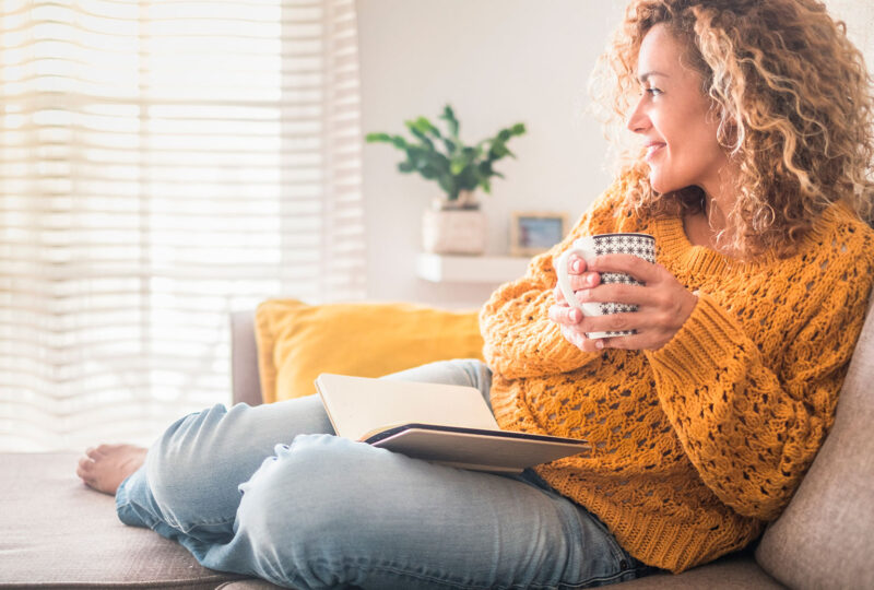relaxed woman sitting with a mug and book