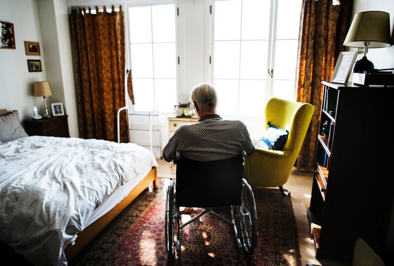older man in wheelchair in a bedroom