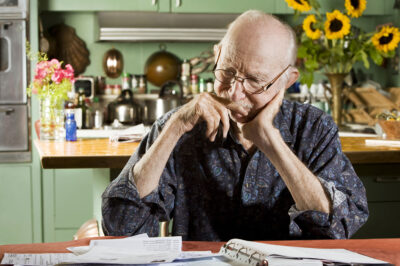 senior man sitting at table looking at paperwork bills