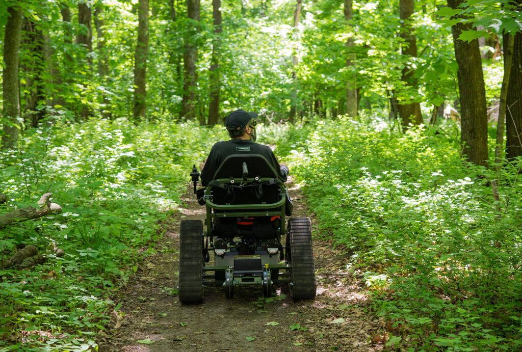 Man in all-terrain chair on a trail in the woods