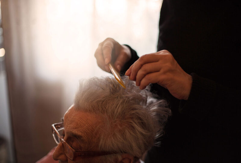someone combing senior person's hair