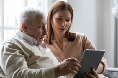 older man, younger woman using tablet