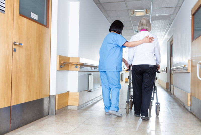 nursing walking with arm around woman in nursing home