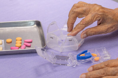 elderly hands sorting and splitting pills