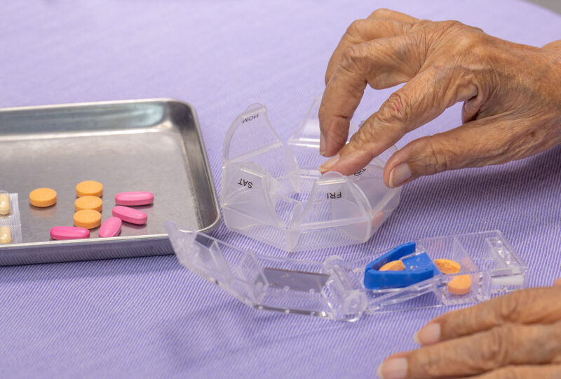 elderly hands sorting and splitting pills