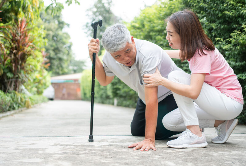 younger woman helping older man who has fallen with cane