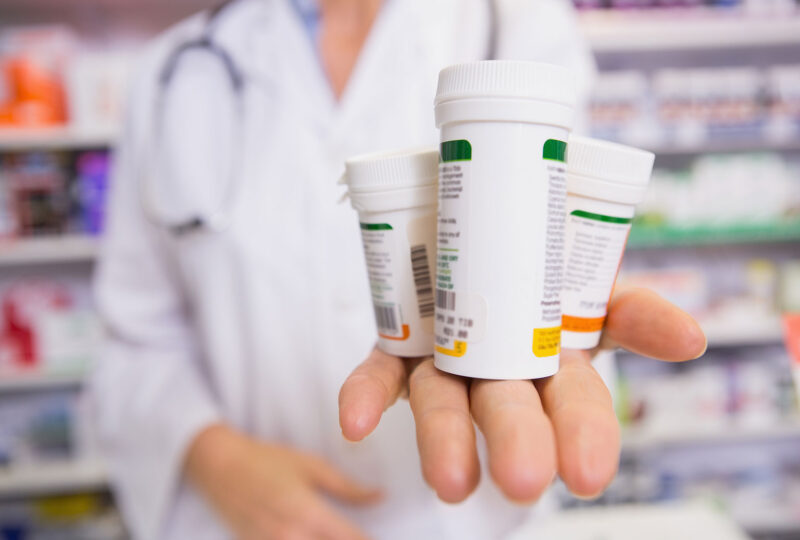 pharmacist holding medication prescription bottles in hand