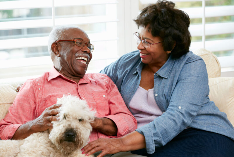 older couple sitting on couch with dog