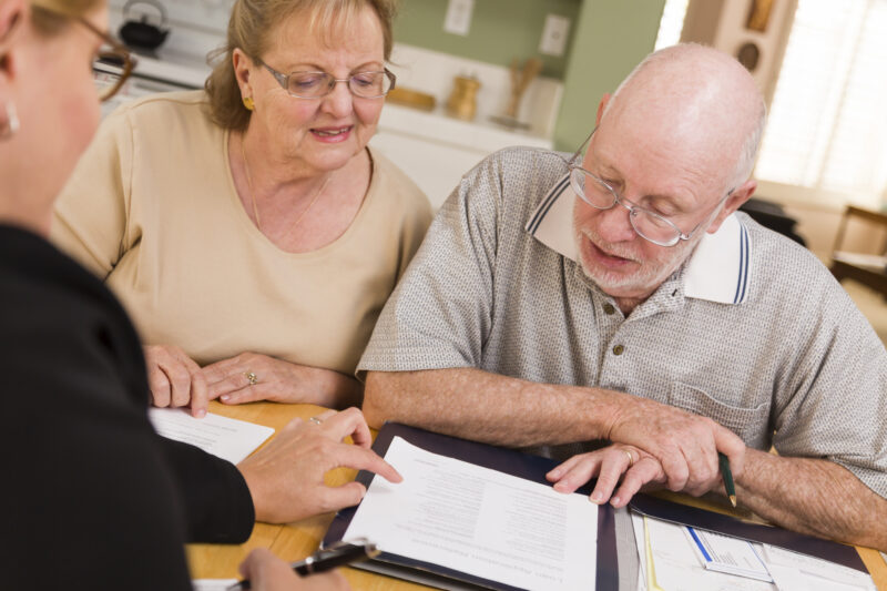 Insurance agent reviewing papers with a senior couple