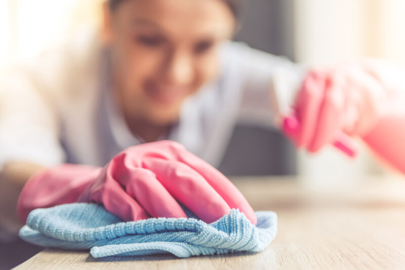Woman wearing protective gloves cleaning a table