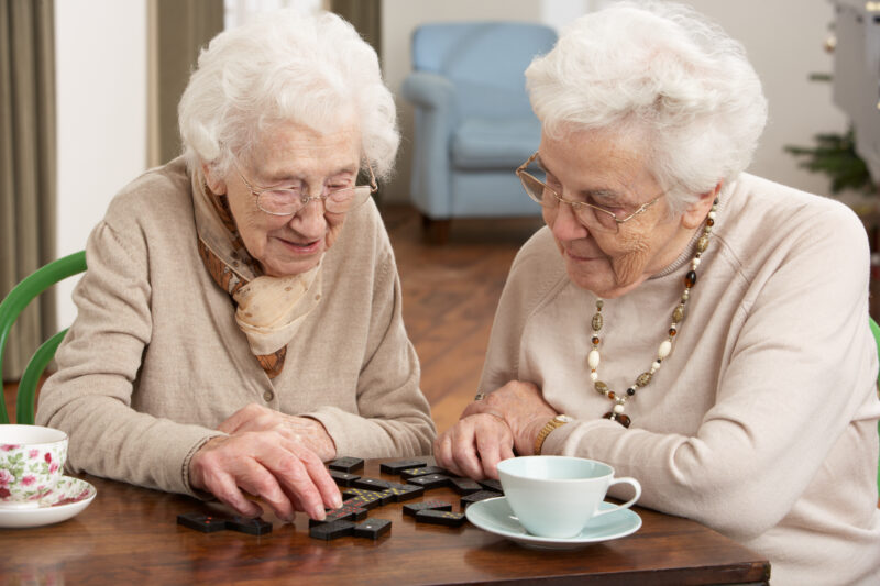 Two senior women playing dominoes at an adult day care center
