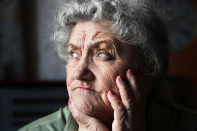 older woman with upset face on hands