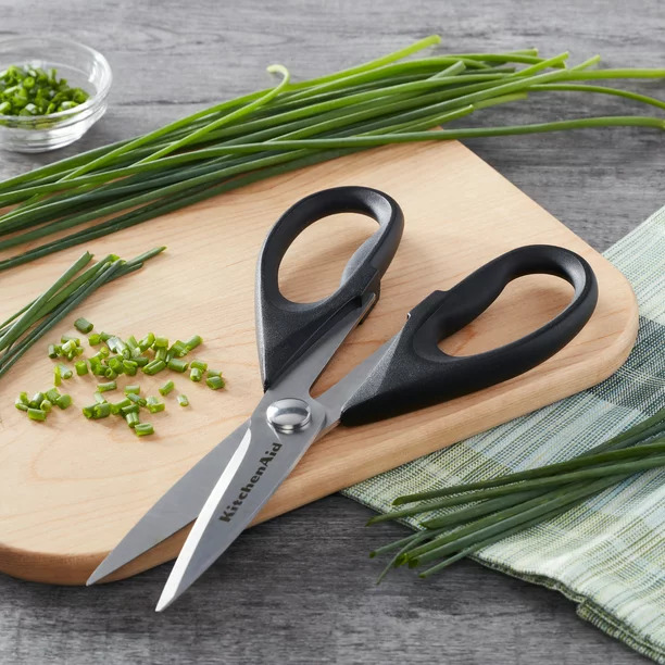scissors on a cutting board by green onions