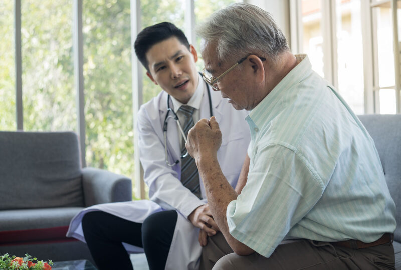 older man sitting in doctor's office, doctor looking at him