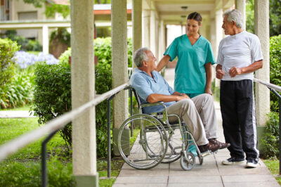 two men speak with a nurse at senior living facility