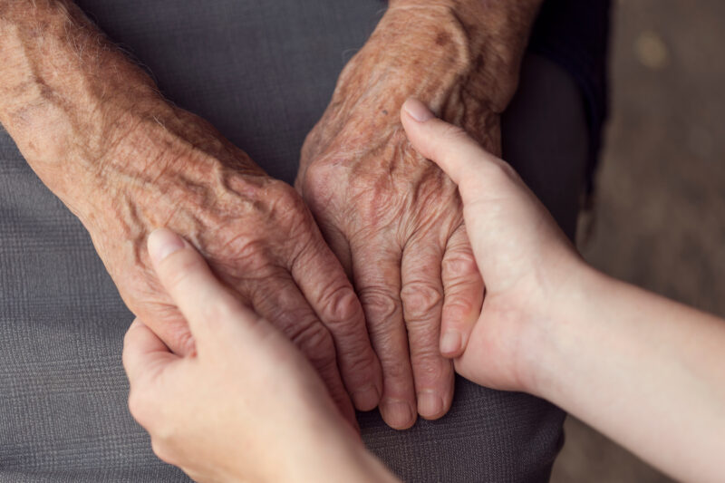 Older person and younger person holding hands