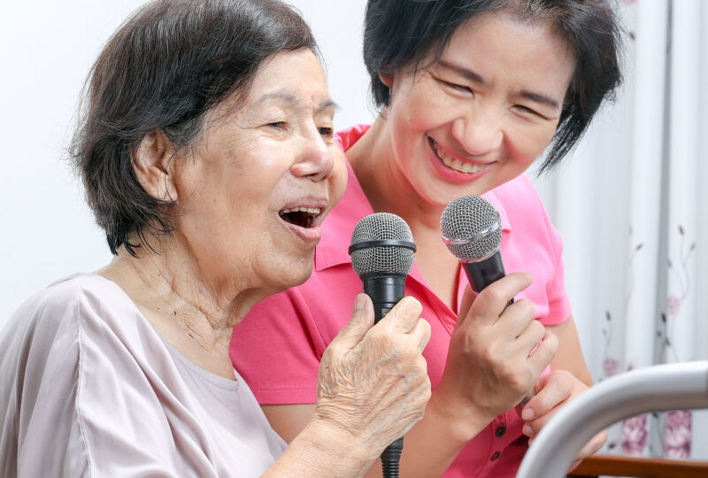older and younger woman singing into microphones
