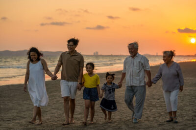 family walking hand in hand on the beach at sunset