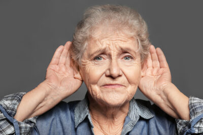 senior woman holding hands to ears