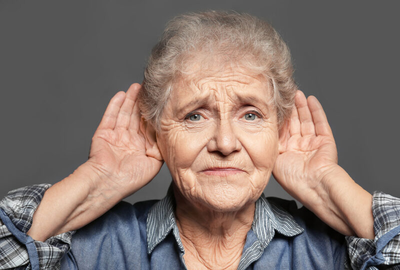 senior woman holding hands to ears