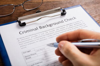 hand holding a pen over a background check form