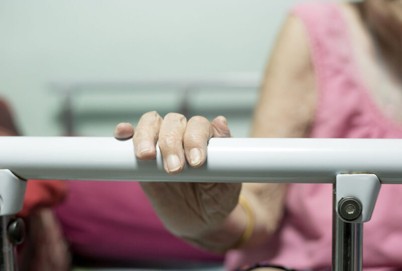 older woman holding onto bed rail
