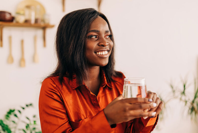 woman smiling and holding a glass of water