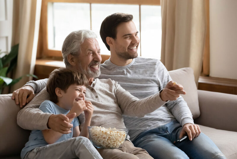 three generations of men watching TV with popcorn
