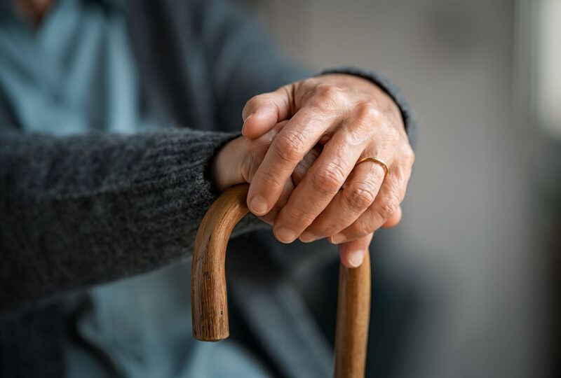 an older person's hands resting on a cane