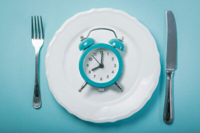 alarm clock on a plate in between a knife and fork
