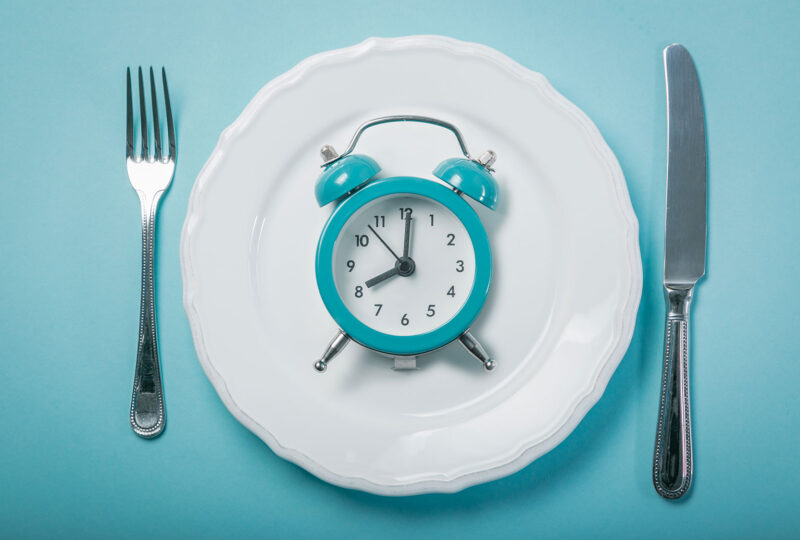 alarm clock on a plate in between a knife and fork