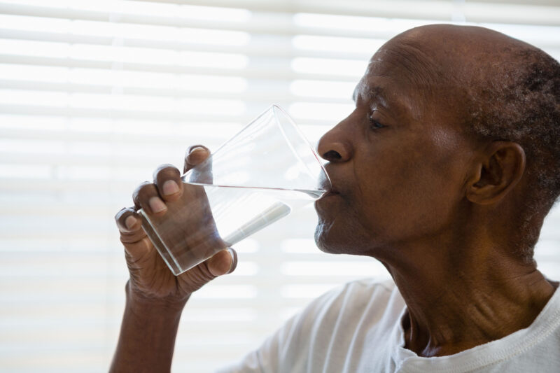 profile view of an older man drinking a glass of water