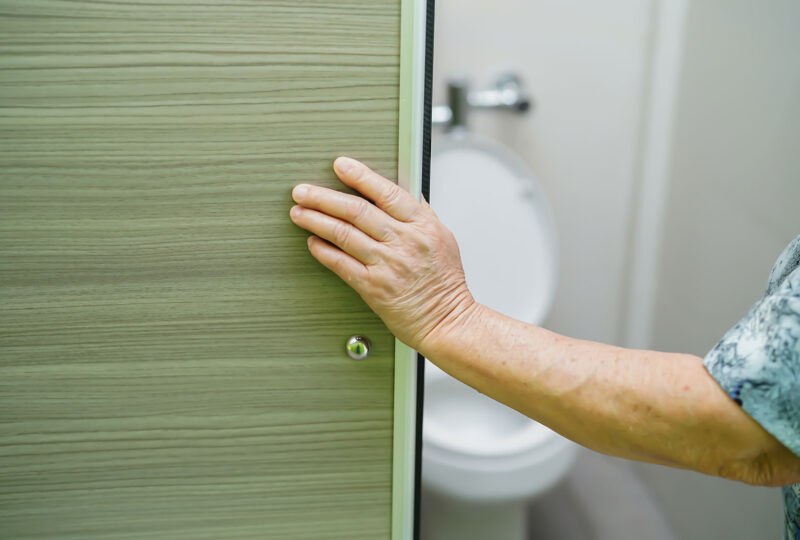 person opening bathroom door, toilet in background