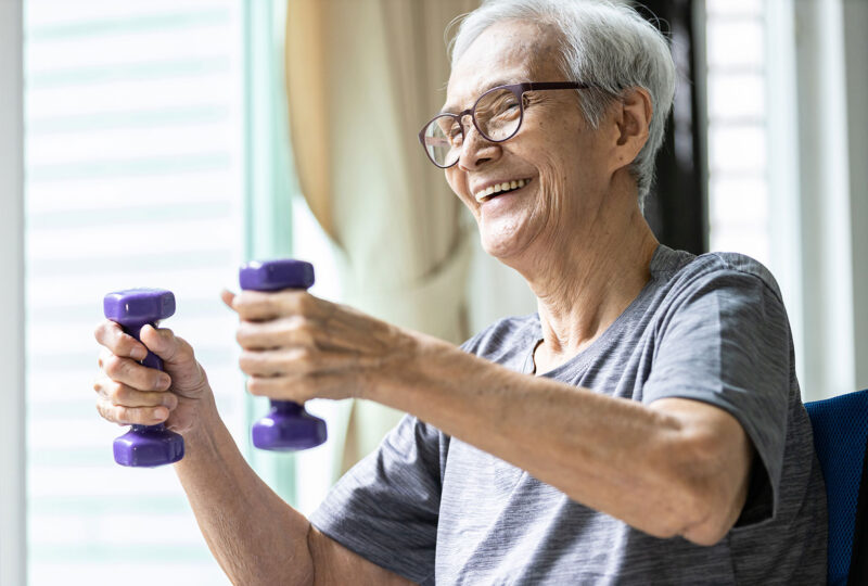 older person lifting hand weights and laughing or smiling