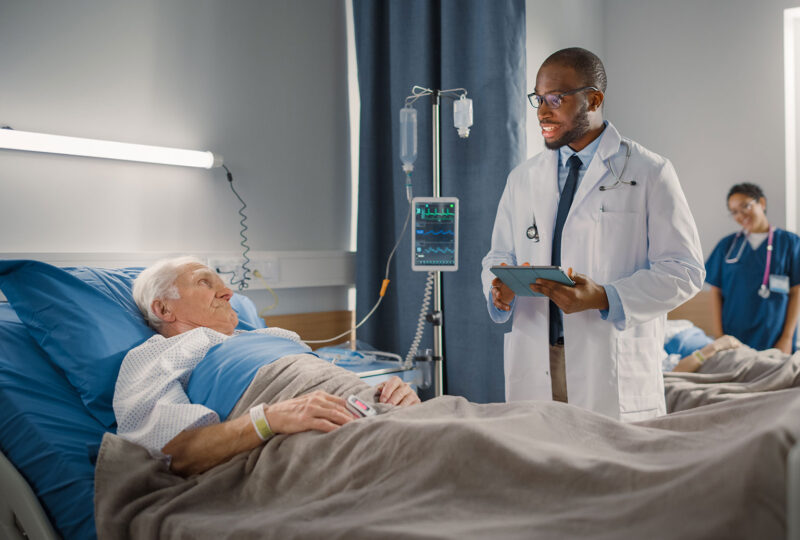 doctor speaking to senior man in hospital bed