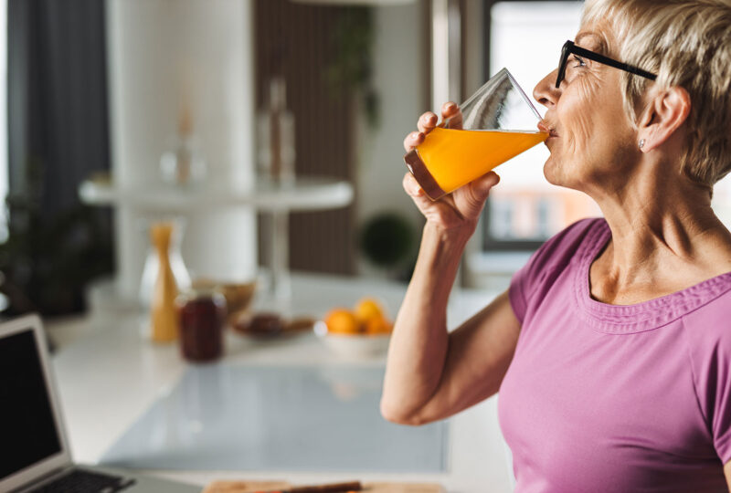 older woman drinking beverage in kitchen