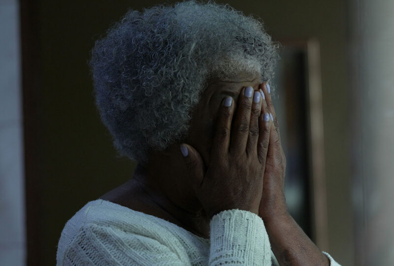 older woman covering her face with her hands